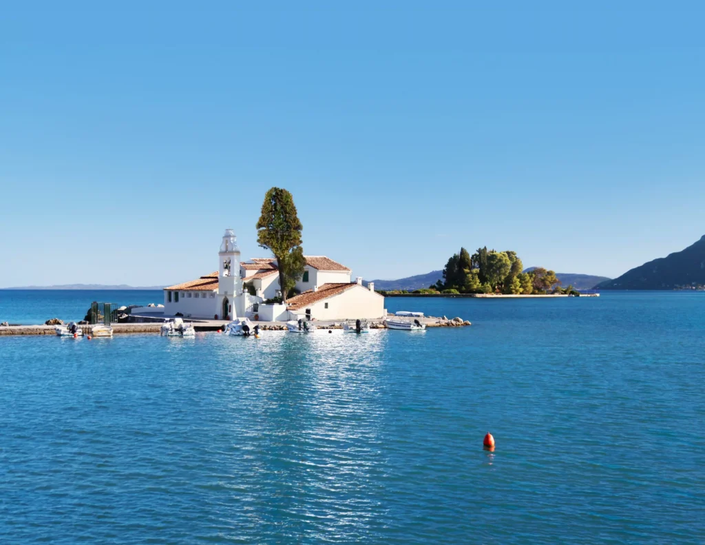 A boat near an island monastery in clear blue water in Corfu, Greece