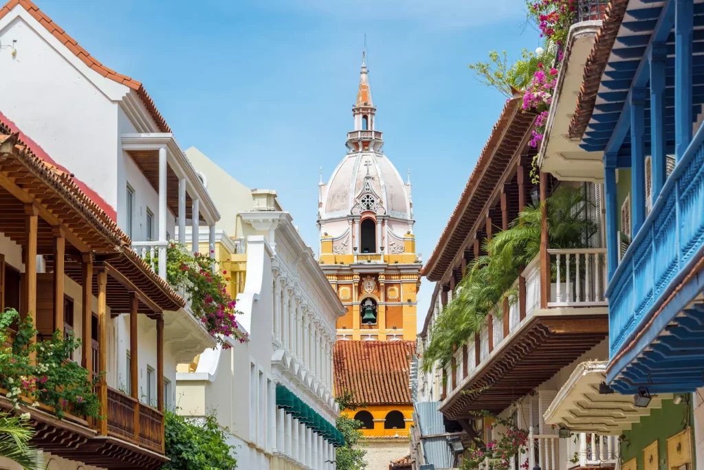 A picturesque view of Cartagena's charming streets with a historic tower in the background adorned with vibrant balconies