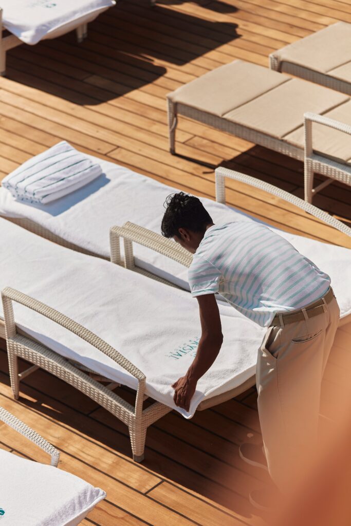 Crew member arranging pool deck loungers aboard Crystal