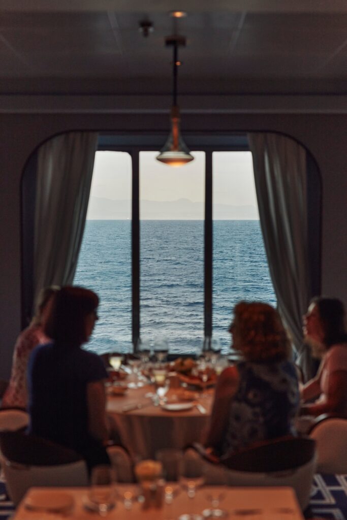 Dining table set beside a large window overlooking the sea aboard Crystal