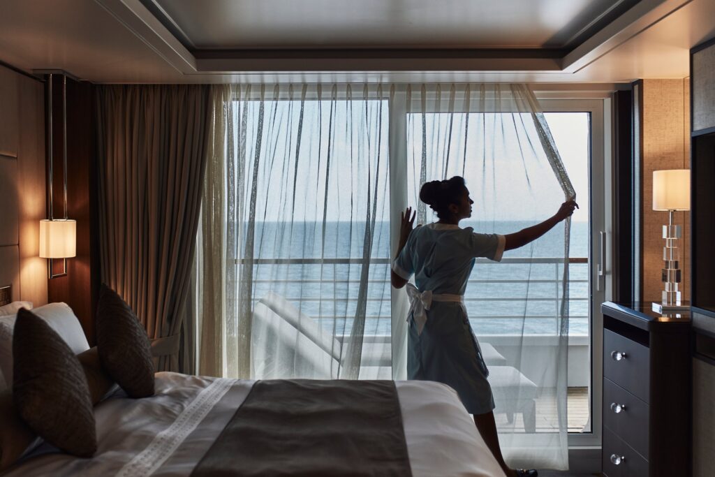 Guest opening the curtains to an ocean view in a Crystal suite