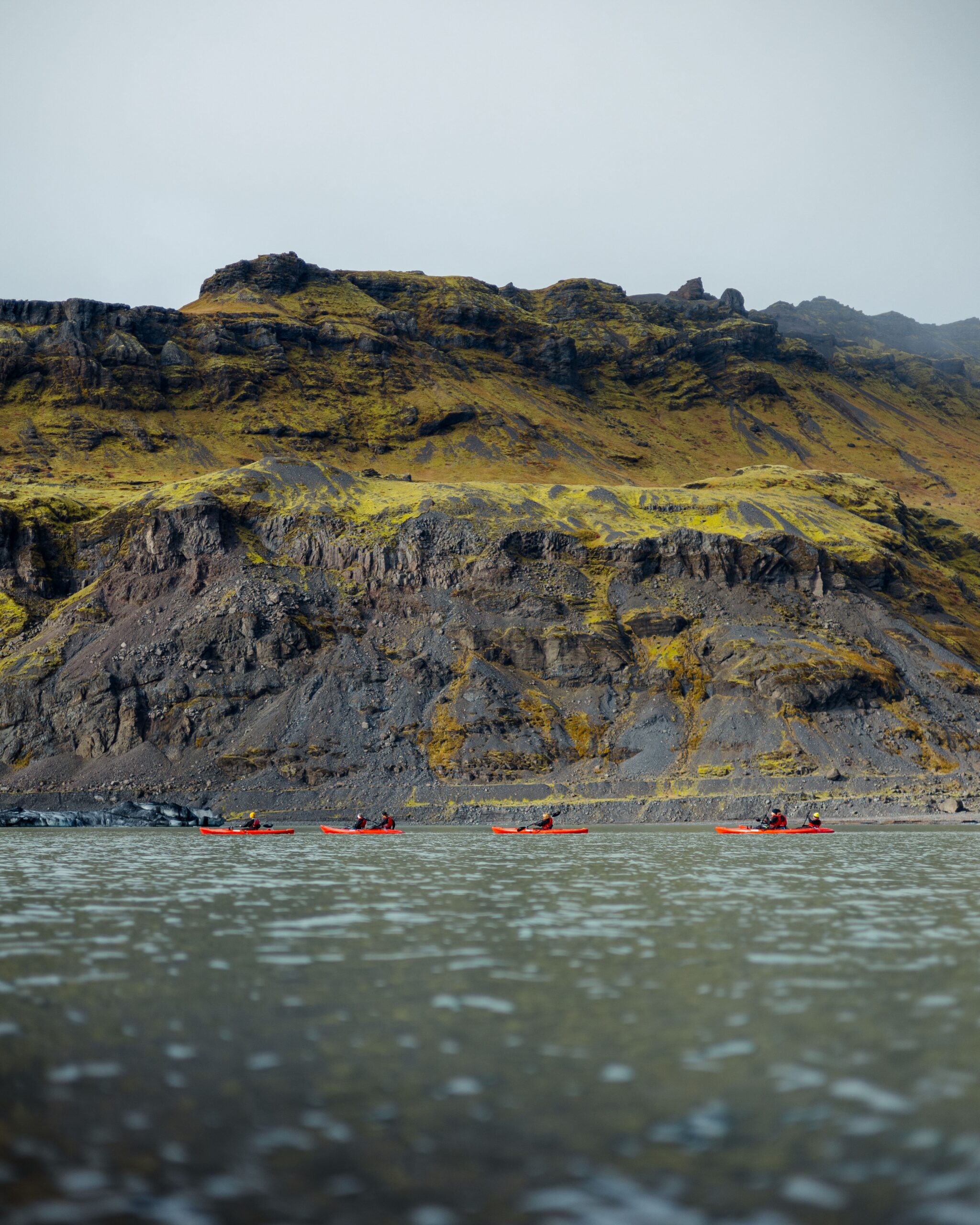 Kayakers paddling beneath rugged sea cliffs on an active adventure trip