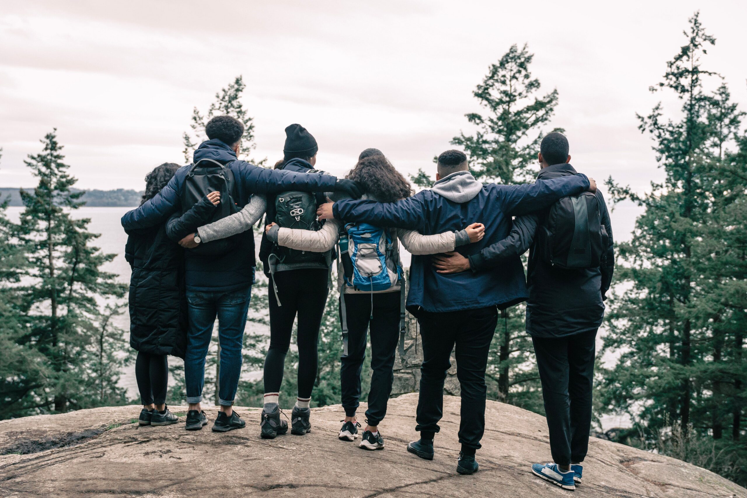 Group of friends standing arm in arm overlooking a lake