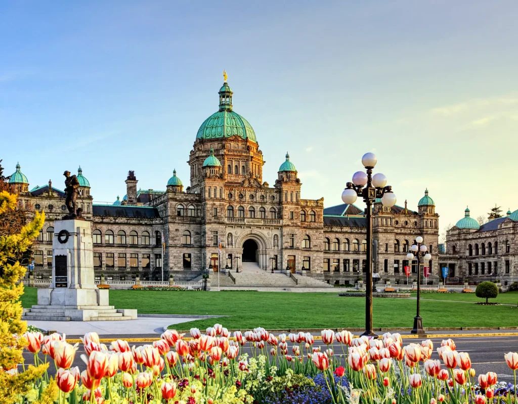 The iconic Parliament Building in Victoria surrounded by lush gardens and a clear sky