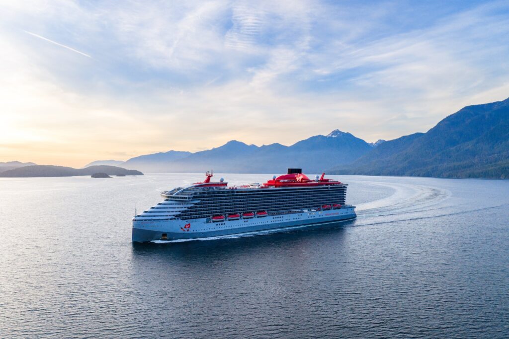 Virgin Voyages ship cruising past mountains in Alaska